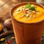 A thick, creamy glass of traditional mango lassi garnished with pistachios, representing the ultimate Mango Lassi Recipe.